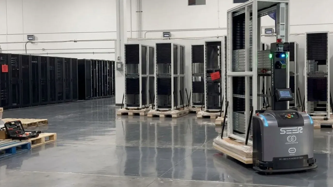 Robot móvil SEER transportando un rack sobre tarima en una nave de almacén.